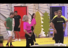 a group of people are standing around a yellow mat in a room .