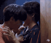 a couple of men are kissing each other while standing next to each other against a wall .