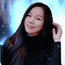 a woman wearing a black turtleneck sweater holds her hair