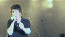 a man singing into a microphone with the letter d on the bottom left