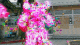 a pink robot is surrounded by balloons in a playground