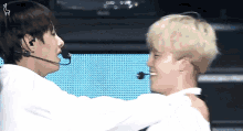 two men are hugging each other and one has a microphone on his head