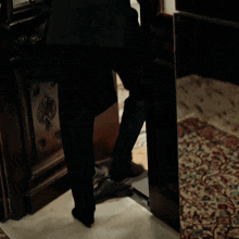 a person standing in front of a door with a floral rug on the floor