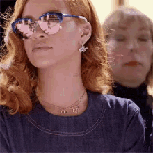 a close up of a woman wearing sunglasses and a necklace .