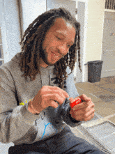 a man with dreadlocks wearing a grey hoodie that says ' ncl ' on it