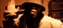 a man wearing a hat stands in front of a marshall amp