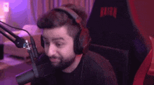 a man wearing headphones is sitting in front of a microphone in a chair .