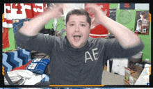 a man wearing a shirt that says ae holds his hands in the air