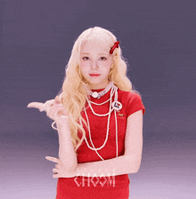 a blonde woman wearing a red dress and pearls is pointing