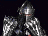 a man in a knight 's armor covering his face