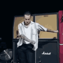 a man is standing in front of a marshall amplifier
