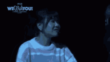 a woman in a pink and white striped sweater is giving a middle finger while standing in the dark .