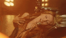a woman is laying on the floor holding a microphone and smiling .