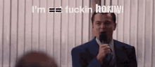 a man in a suit and tie is holding a microphone and saying i 'm fuckin horny
