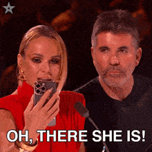 a man and a woman looking at a cell phone with the words oh there she is