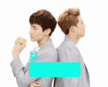 two young men are standing back to back and one is holding a lemon .