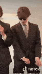a man in a suit and tie is dancing in a tiktok video .