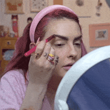 a woman with red hair is applying eyebrow pencil to her eyebrows