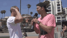 a man in a pink shirt is holding a microphone that says lsd on it