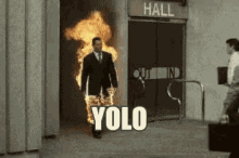 a man in a suit is walking through a hallway with fire coming out of his pants and the words yolo written on the ground