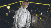 a man in a hoodie stands in front of a crime scene