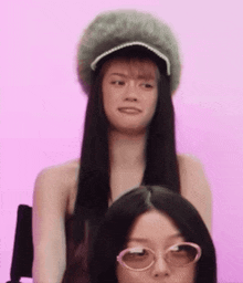 a woman wearing a fur hat and sunglasses looks at the camera