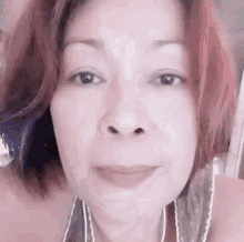 a close up of a woman 's face with red hair and a very small nose .