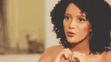 a woman with curly hair is making a heart shape with her hands