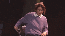 a woman in a purple sweater with a pink bow on her head is sitting in a chair