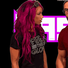 a woman with pink hair wearing a shirt that says feel the glow
