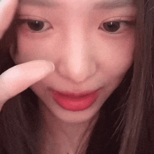 a close up of a girl 's face with a finger on her nose