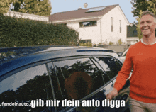 a man in an orange sweater is standing in front of a blue car with the words gib mir dein auto digga written on the bottom