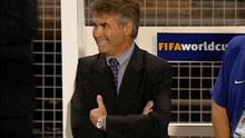 a man in a suit giving a thumbs up in front of a sign that says fifaworldcup