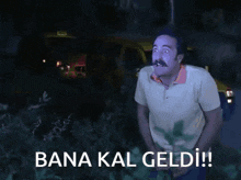 a man with a mustache is standing in front of a car with the words bana kal geldi written below him