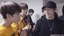 a group of young men are standing next to each other and talking .