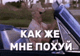 a man in a cowboy hat is driving a car with the words " как же мне похуй " written on the screen