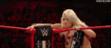 a woman is kneeling in a wrestling ring with a sign that says w on it .
