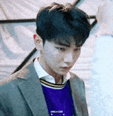 a young man wearing a suit and a purple sweater has the word vanilla cube on his shirt