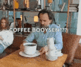 a man is sitting at a table with a stack of coffee cups on it .