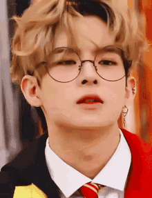 a close up of a young man wearing glasses and a red tie