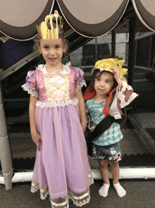 a little girl in a princess dress stands next to another little girl in a pirate outfit