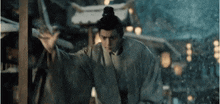 a man in a kimono is standing in the snow with his hand up .