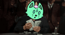 a man sitting at a table holding a bunch of money with a cat on his head