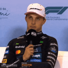 a man wearing a mclaren hat holds a microphone