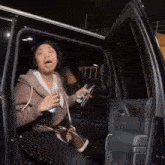 a woman is sitting in the back seat of a car holding a bottle of water and a cell phone .
