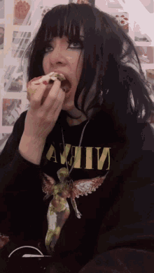 a girl wearing a black shirt that says nirvana is eating a cupcake