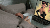 a person is holding a cup of coffee in front of a laptop with a comic on the screen