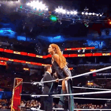 a woman in a green dress is standing in a wrestling ring holding a referee 's hand .