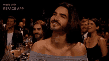 a man with long hair and a beard is wearing a woman 's top .