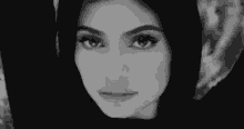 a black and white photo of a woman 's face with her arms over her head .